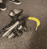 A robot dog with a sleek visor and antenna sits in front of a banana