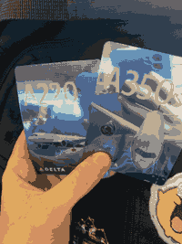 Two shiny foil cards with images of basically identical looking white airplanes: the A220 and A350 respectively. The background is blue and white.