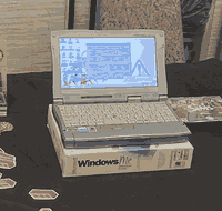 A miniature white laptop on top of a Windows Me box with an OS-tan desktop wallpaper.